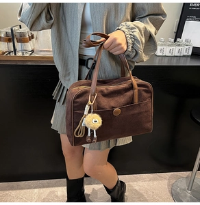 Detail of vintage matte brown tote bag with suede texture and plush yellow charm