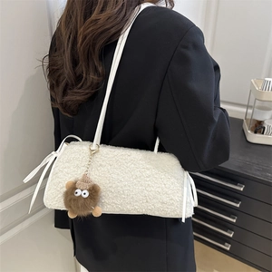 Mini sac bandoulière en polaire blanche avec breloque monstre porté par un mannequin