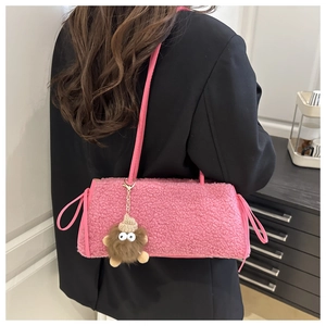 Dettaglio borsa a spalla in peluche rosa con ciondolo a mostro su una modella