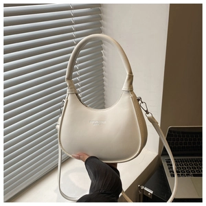 Detailed view of white leather crescent bag with silver hardware and top handle