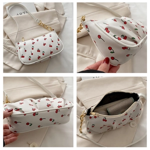 Detail view of white cherry print shoulder bag with gold chain strap and zipper