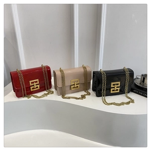 Detailed close-up of glossy patent leather handbags with gold chain straps and metal buckles