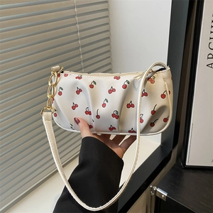 White crescent underarm bag with red cherry print and decorative gold chain strap