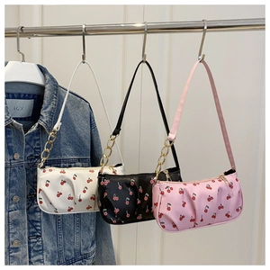 Three half-moon underarm bags in white, black, and pink with red cherry print patterns