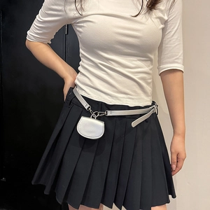 Mini sac décoratif argenté sur une jupe plissée noire pour un look de mode élégant
