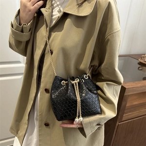 Fashionable black woven bucket bag with gold chain strap and pearl drawstring charms