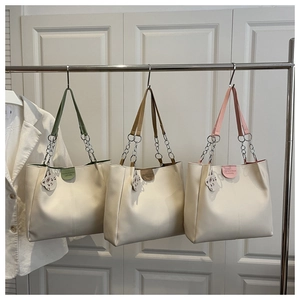 Three ivory tote bags with colorful leather tags and cat charms on a metal hanger