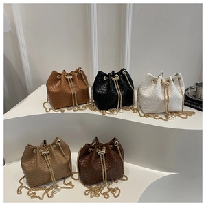 Detailed view of textured woven bucket bags with gold chain drawstrings and pearl beads