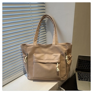 Detail of khaki tote bag featuring large front flap pocket and drawstring side pockets