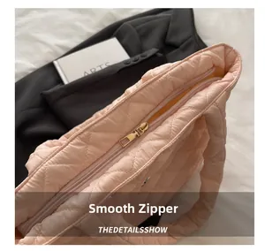 Close-up of smooth golden zipper and pink quilted nylon texture on tote bag