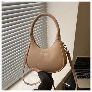 Detail of beige crescent moon bag showing matte faux leather and fashion logo print