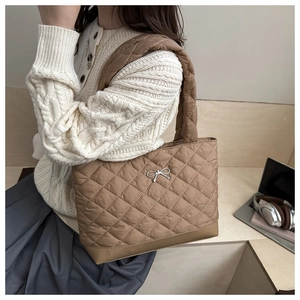 Close-up of brown quilted tote bag with silver bow detail and large diamond stitching