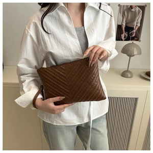 Close-up of brown leather clutch with V-quilted stitching and silver stud details