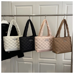 Detail of four quilted tote bags with metallic bow charm in white, black, pink, and brown