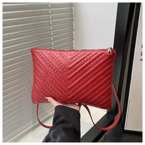 Detail of red envelope bag with V-quilted pattern and metallic rivet studs