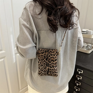 Chic leopard print mini crossbody bag with metal chain strap worn by a model