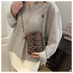 Detail of leopard print crossbody phone bag with gold metal chain strap on model