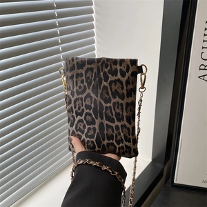 Detail of leopard print mini crossbody bag with golden chain strap held by model