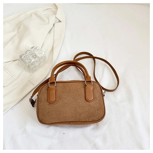 Vue détaillée de la texture marron et de la poignée en cuir lisse du sac Boston