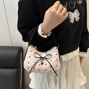 Pink jacquard shoulder bag with bow embroidery and heart pendant shown on model