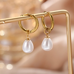 Macro shot of elegant gold hoop earrings featuring white teardrop imitation pearls