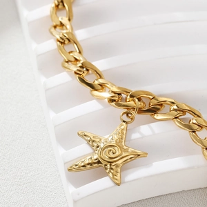 Detailed macro view of a gold starfish charm with spiral texture on a Cuban chain anklet