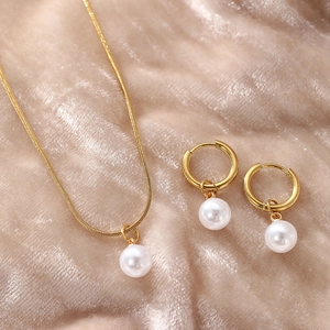 Parure élégante de bijoux en perles dorées avec collier et boucles sur velours champagne