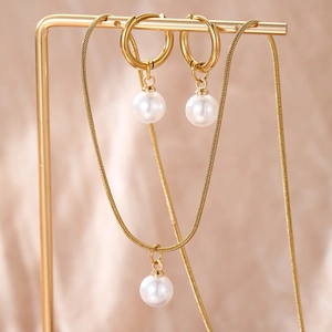Détail de parure collier et boucles d'oreilles perles dorées sur support élégant