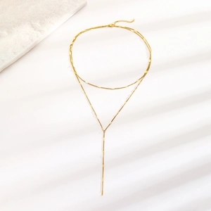 Macro view of golden double-layered Y-shaped necklace with fine metal square link texture