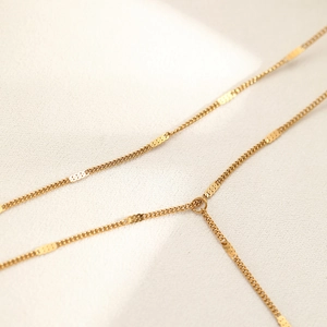 Macro detail of gold-plated Y-shaped necklace with flat polished discs and round links