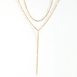 Detail of a double-layered gold Y-shaped tassel necklace with geometric flat square links
