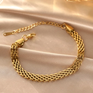 Macro view of gold braided mesh bracelet with lobster clasp and S.STEEL tag on silk