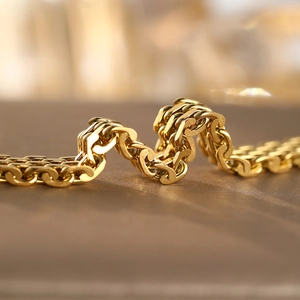 Macro view of 18K gold plated stainless steel woven chain bracelet with polished finish