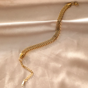 Detailed view of 18K gold plated multi-strand flat chain bracelet on champagne silk fabric