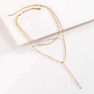 Détail du collier en Y doré à deux rangs montrant les disques brillants et le fermoir mousqueton