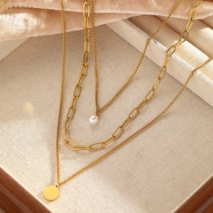 Detailed view of triple-layered gold necklace with imitation pearl and round pendant