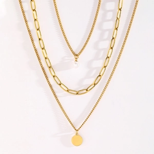 Detailed view of layered gold-tone necklace with pearl and round metal tag charms