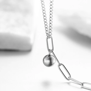 Vue détaillée d'une perle argentée polie sur une chaîne de cheville à maillons
