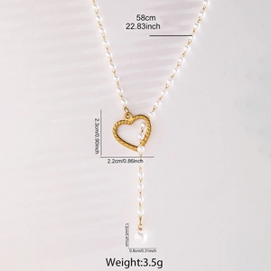 Détail du collier de perles avec pendentif cœur évidé doré et texture torsadée
