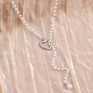 Collier en perles en Y avec pendentif cœur évidé argenté sur velours champagne