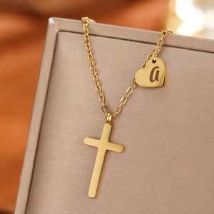 Close-up of golden stainless steel cross and heart pendant necklace with letter a