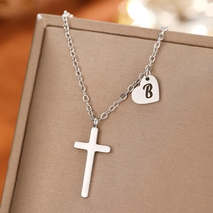 Detail of silver stainless steel cross and heart pendant necklace with letter B engraving