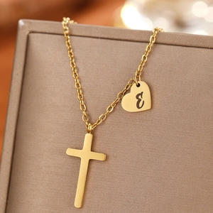 Close-up of gold stainless steel cross and heart pendant necklace with letter E engraving