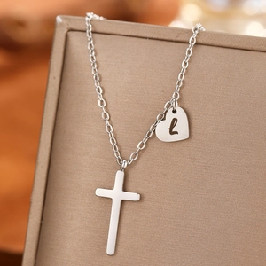 Detail of silver stainless steel necklace with cross and letter L heart pendant