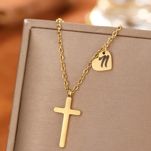 Macro shot of gold cross necklace with heart pendant and engraved letter n on jewelry box