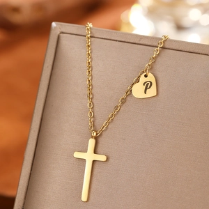 Macro detail of gold-plated stainless steel cross and heart pendant necklace with letter P