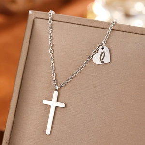 Detailed macro view of a silver heart pendant with letter Q and cross on jewelry box