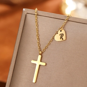 Detail of gold stainless steel necklace with cross and R-letter heart pendant