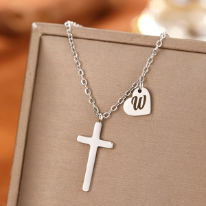 Detailed macro of stainless steel necklace with cross and heart 'W' letter charms