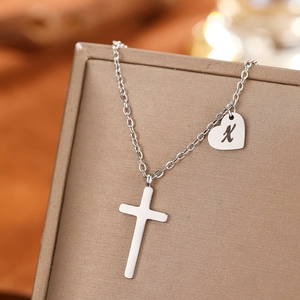 Detail of silver stainless steel cross necklace with an engraved heart initial X pendant
